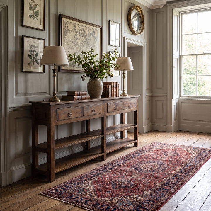Traditional entryway featuring a wooden console table, vintage map art, table lamps, and a red Persian-style rug.