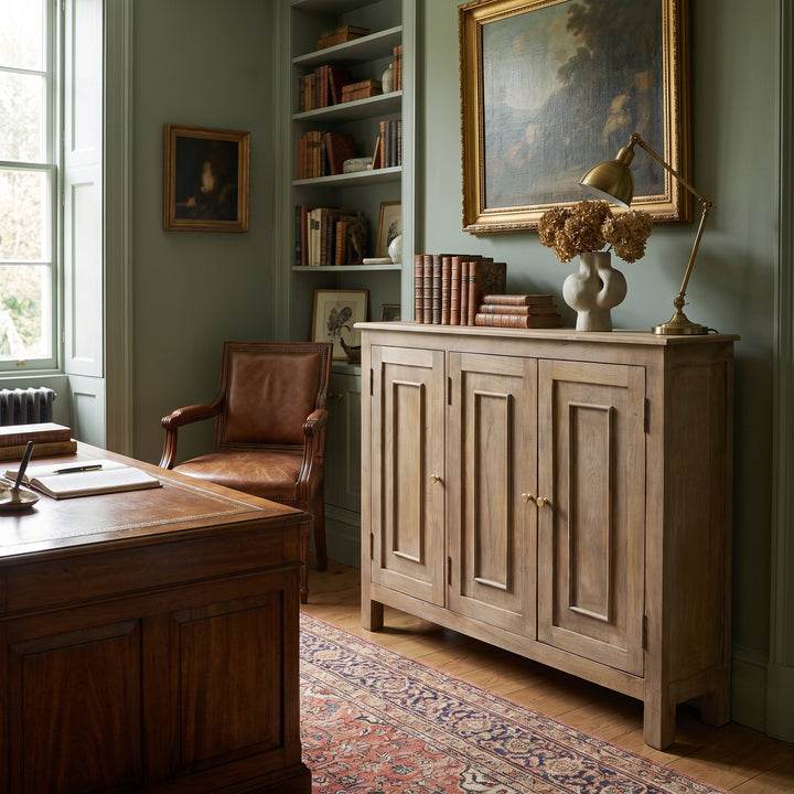 A sophisticated home office featuring a wooden desk, leather chair, built-in bookshelves, and a classic sideboard in a study.
