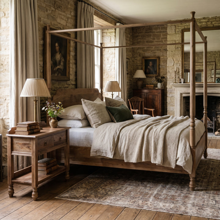Rustic bedroom featuring a wooden four-poster bed, stone walls, and vintage decor in a cozy, traditional English style.