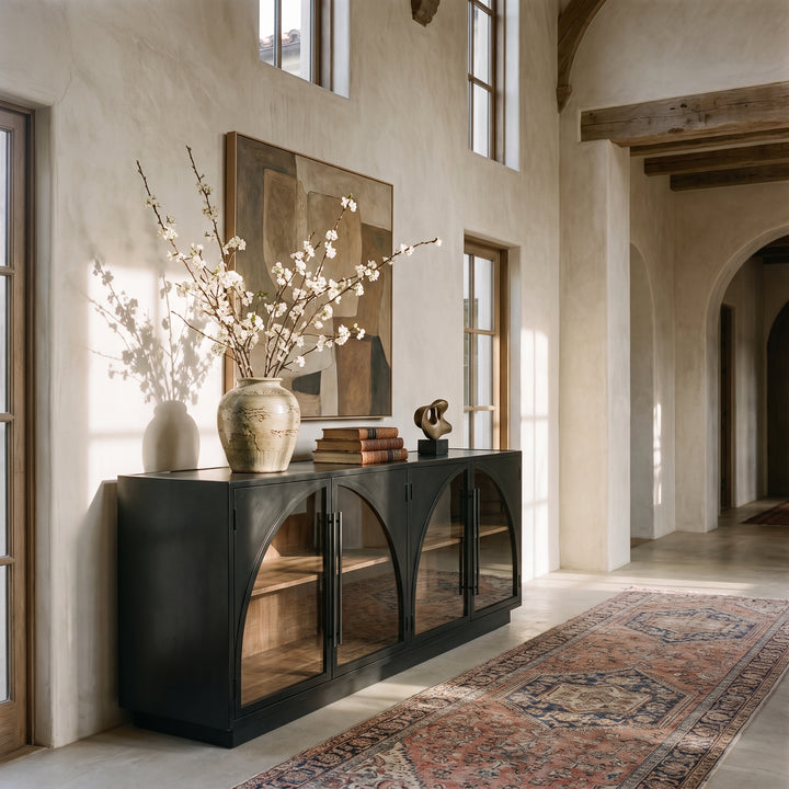 Modern Mediterranean entryway featuring a black arched console table, abstract art, and a vintage-style runner rug.
