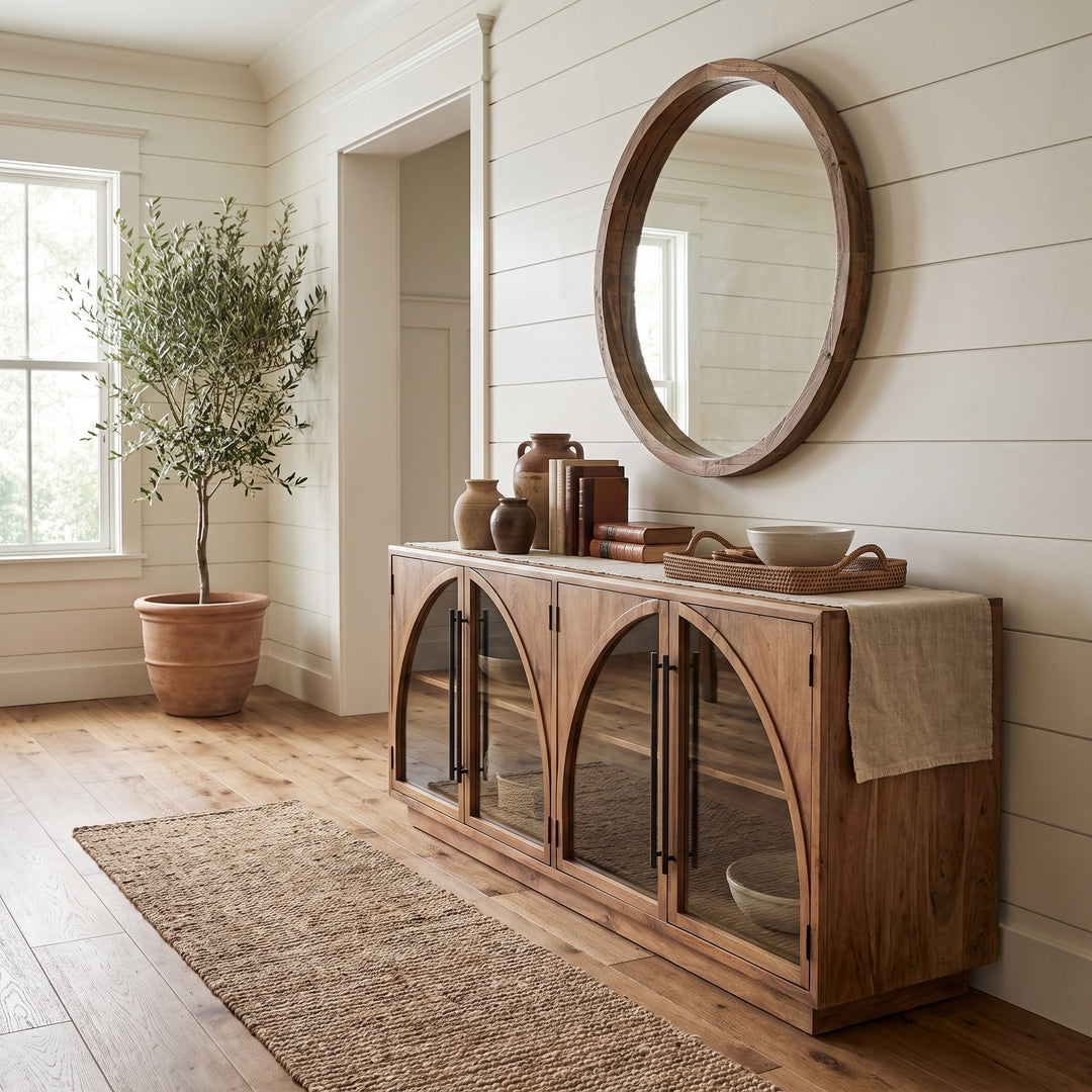 Modern farmhouse entryway featuring a wooden arched console table, round mirror, and potted olive tree on shiplap walls.